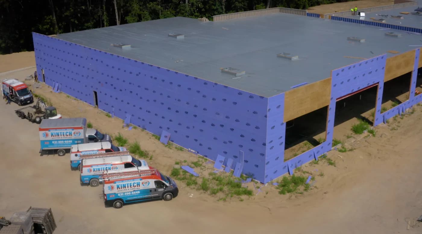 Kintech's vans and box truck lined up at a commercial building under construction