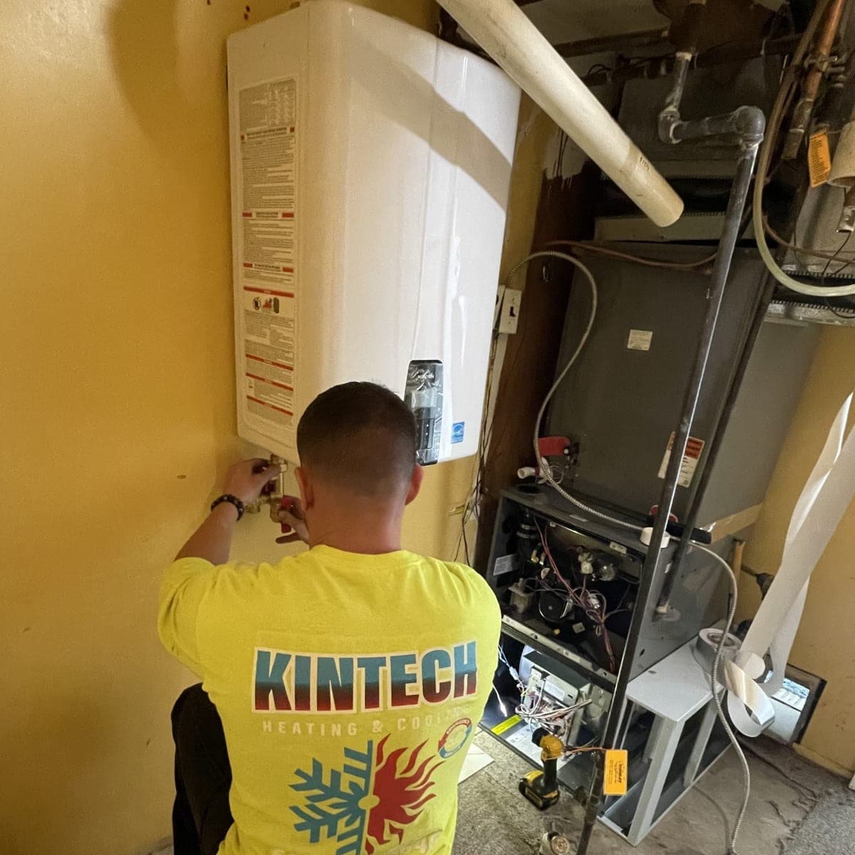 Kintech technician working on a wall-mounted tankless water heater