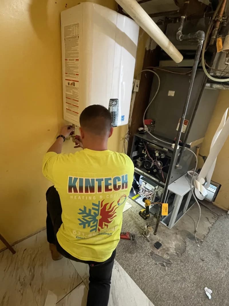 A Kintech technician working on a wall-hung tankless water heater