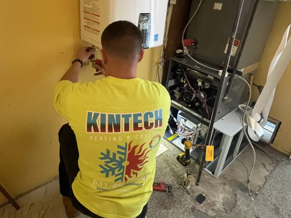 A Kintech technician working on a wall-hung tankless water heater