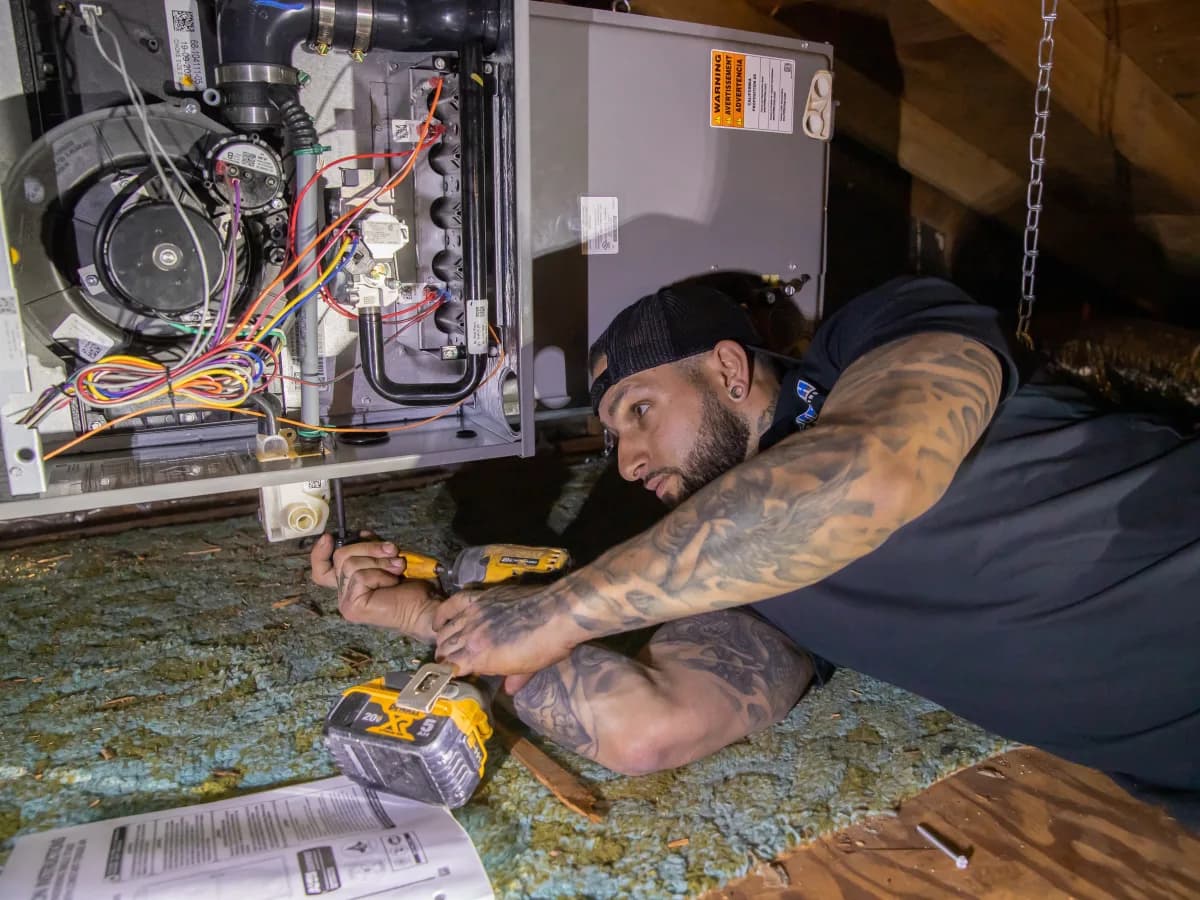 Kintech technician working on an open gas furnace in an attic