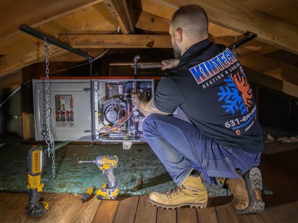 A Kintech technician working carefully on a system in a customer's attic