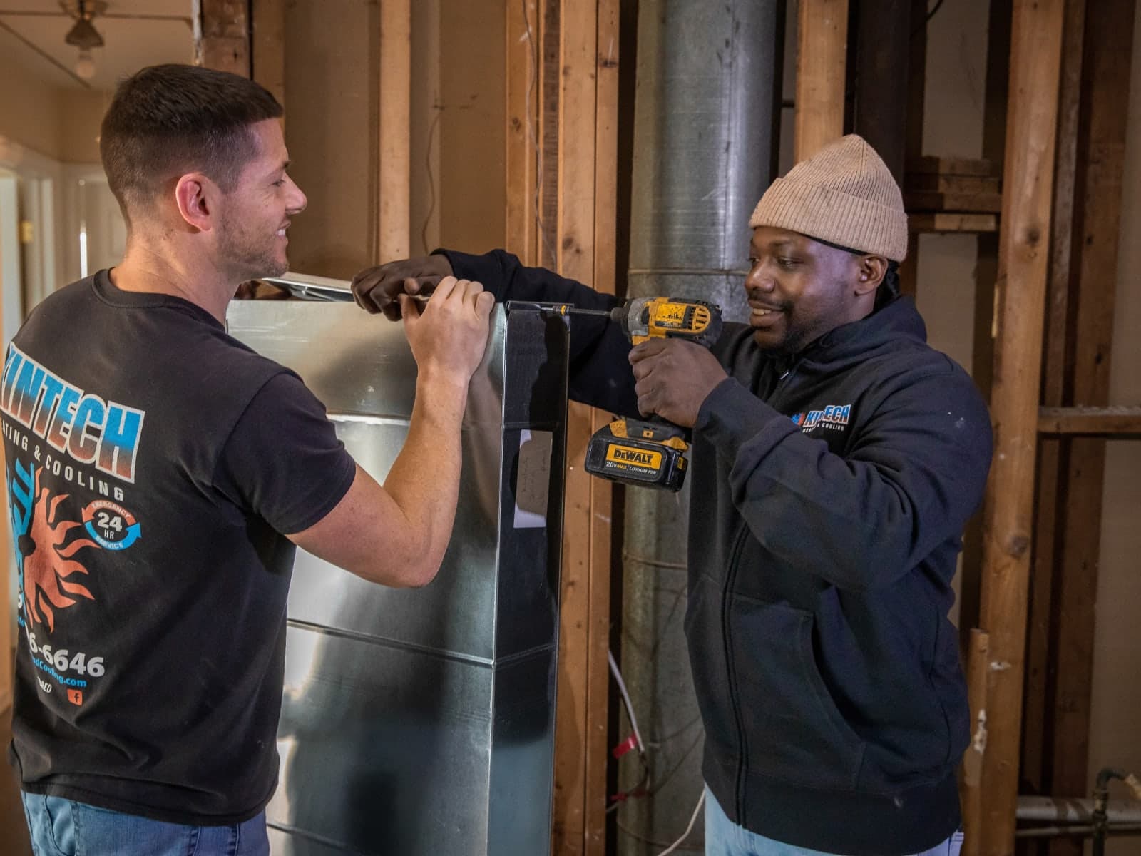 Two Kintech technicians fitting a section of ductwork together on a job