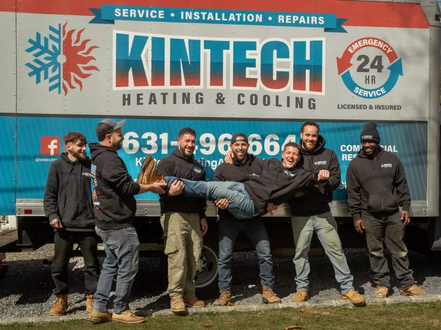 Seven Kintech technicians laughing in front of the box truck, carrying one of the crew sideways