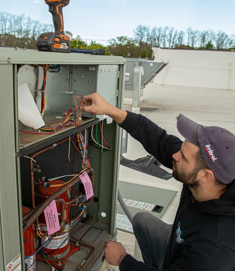 A Kintech technician working on the wiring inside a rooftop unit