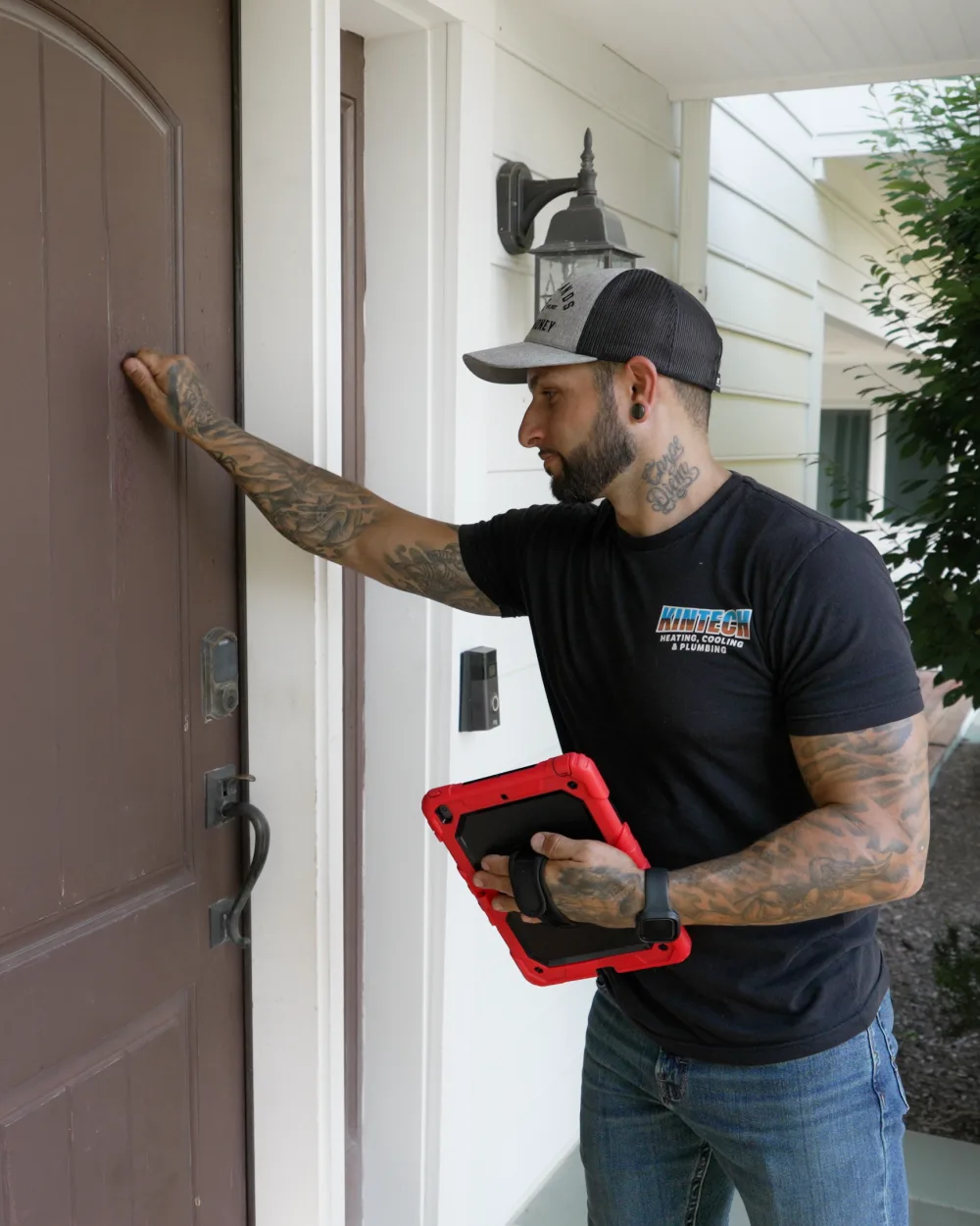 A Kintech technician at a homeowner's front door with a tablet