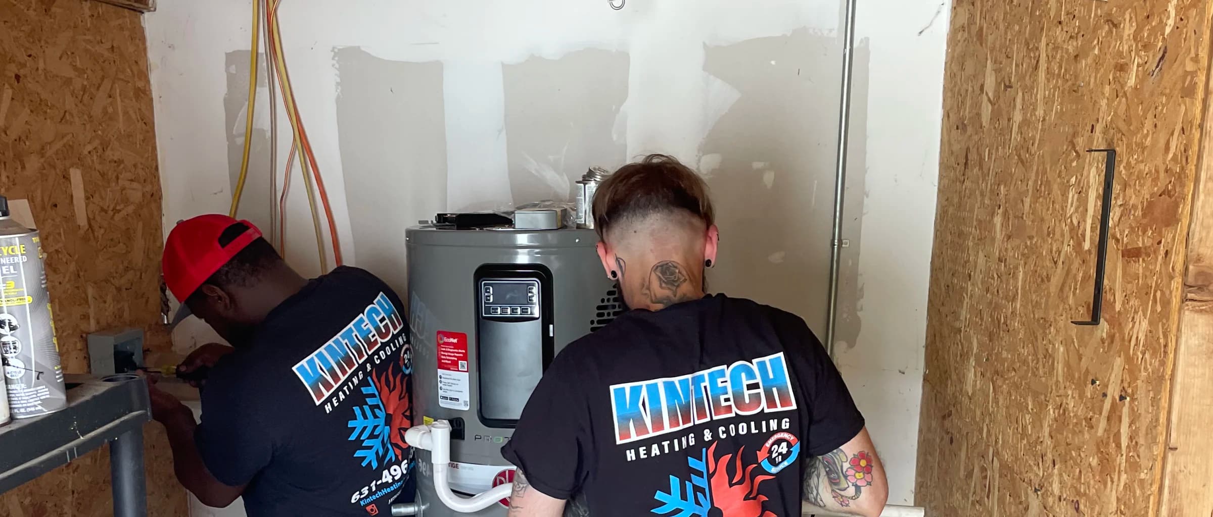 Two Kintech technicians installing a new tank water heater in a Long Island home